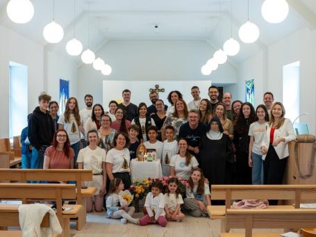 Grupo de pessoas posando juntas em uma igreja, sorrindo e segurando flores.